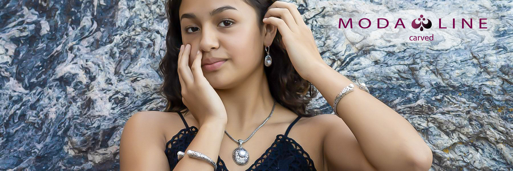 Woman wearing various carved jewelry items with gemstones.