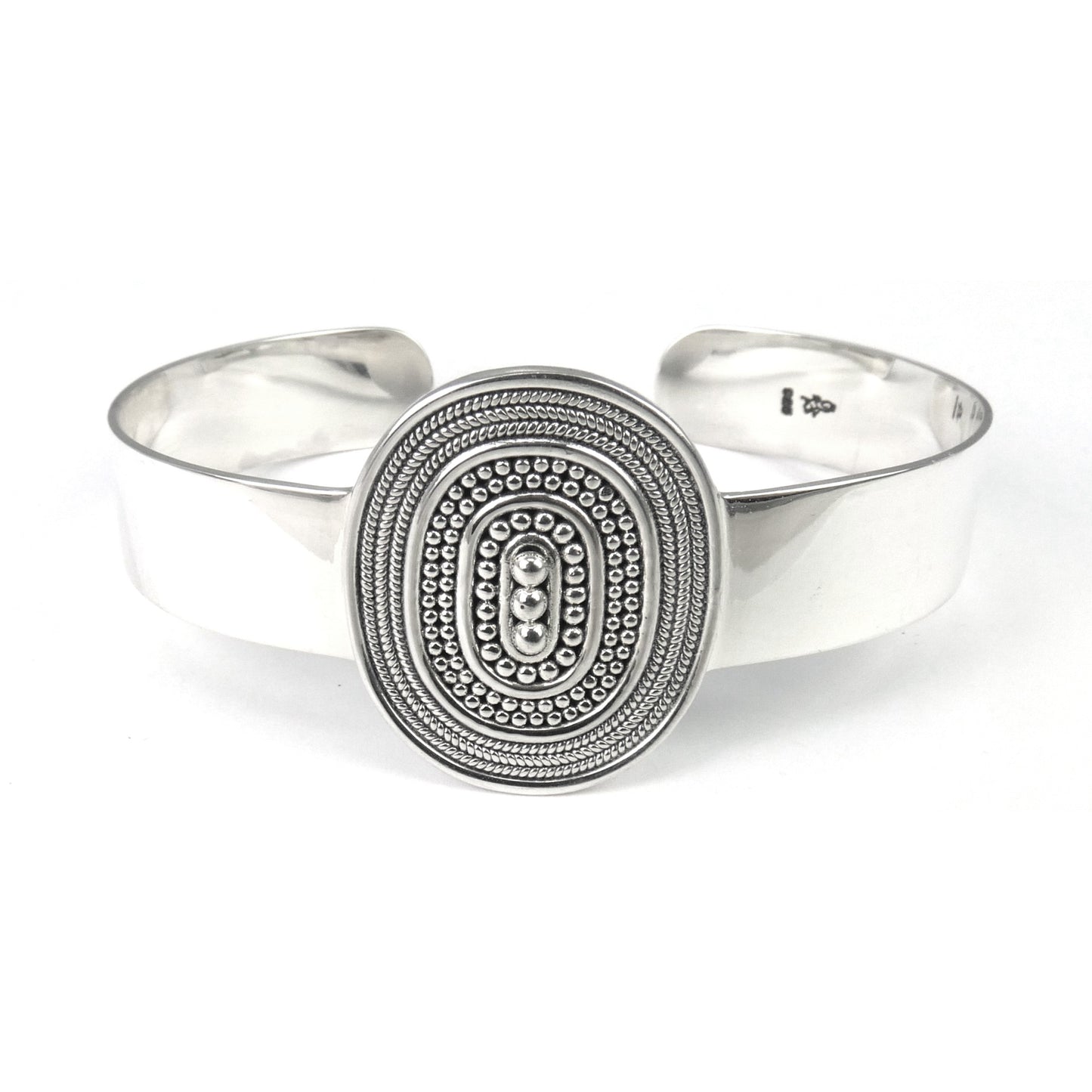 Silver cuff bracelet with one centered oval station with bead and rope decoration.