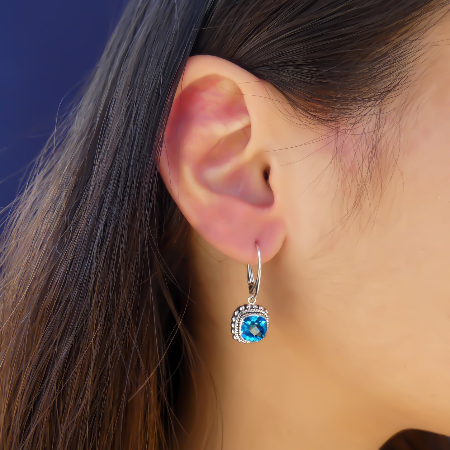 Silver earrings with square blue topaz stones and beaded border.