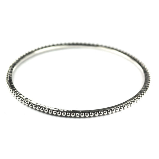 Silver bangle bracelet with a hammered center and beaded edge.