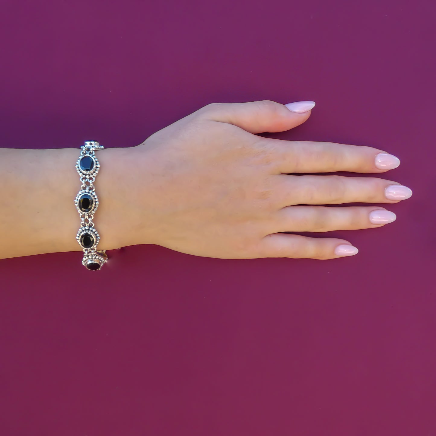 Woman wearing a silver bracelet with oval black onyx links.