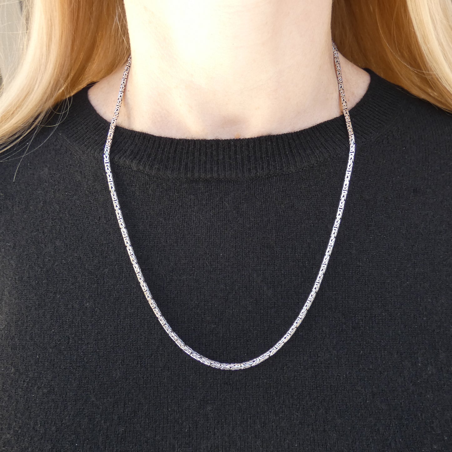 Woman wearing a long silver byzantine chain.