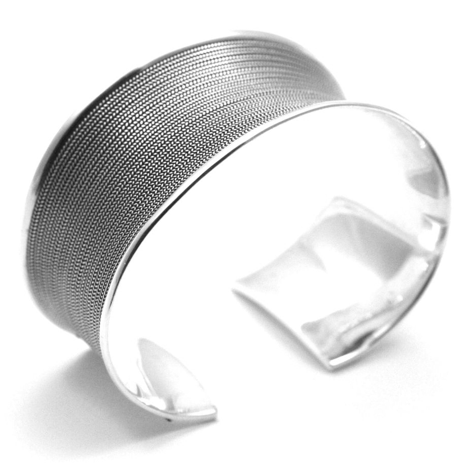 Bold, wide silver cuff bracelet with strands of silver wire running across it.