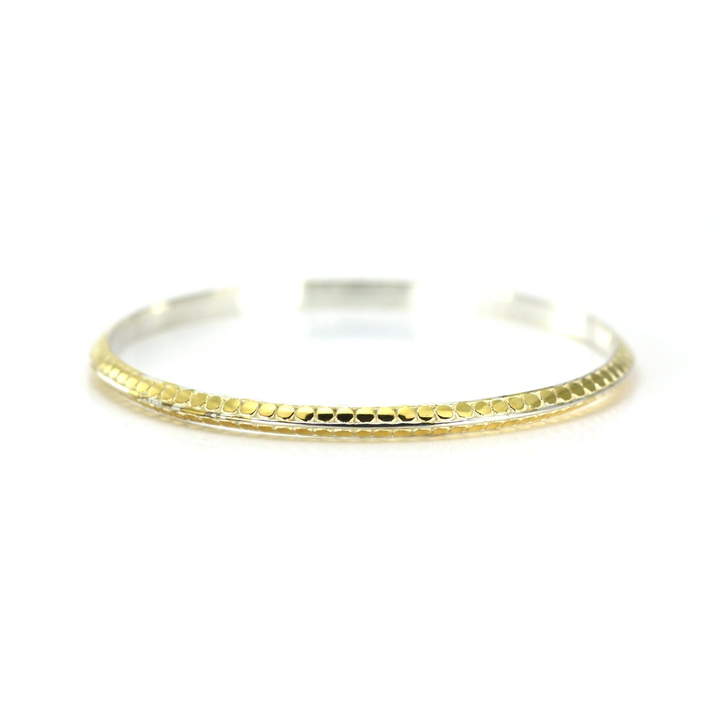 Silver and gold bangle bracelet with flat dots and a triangular profile.