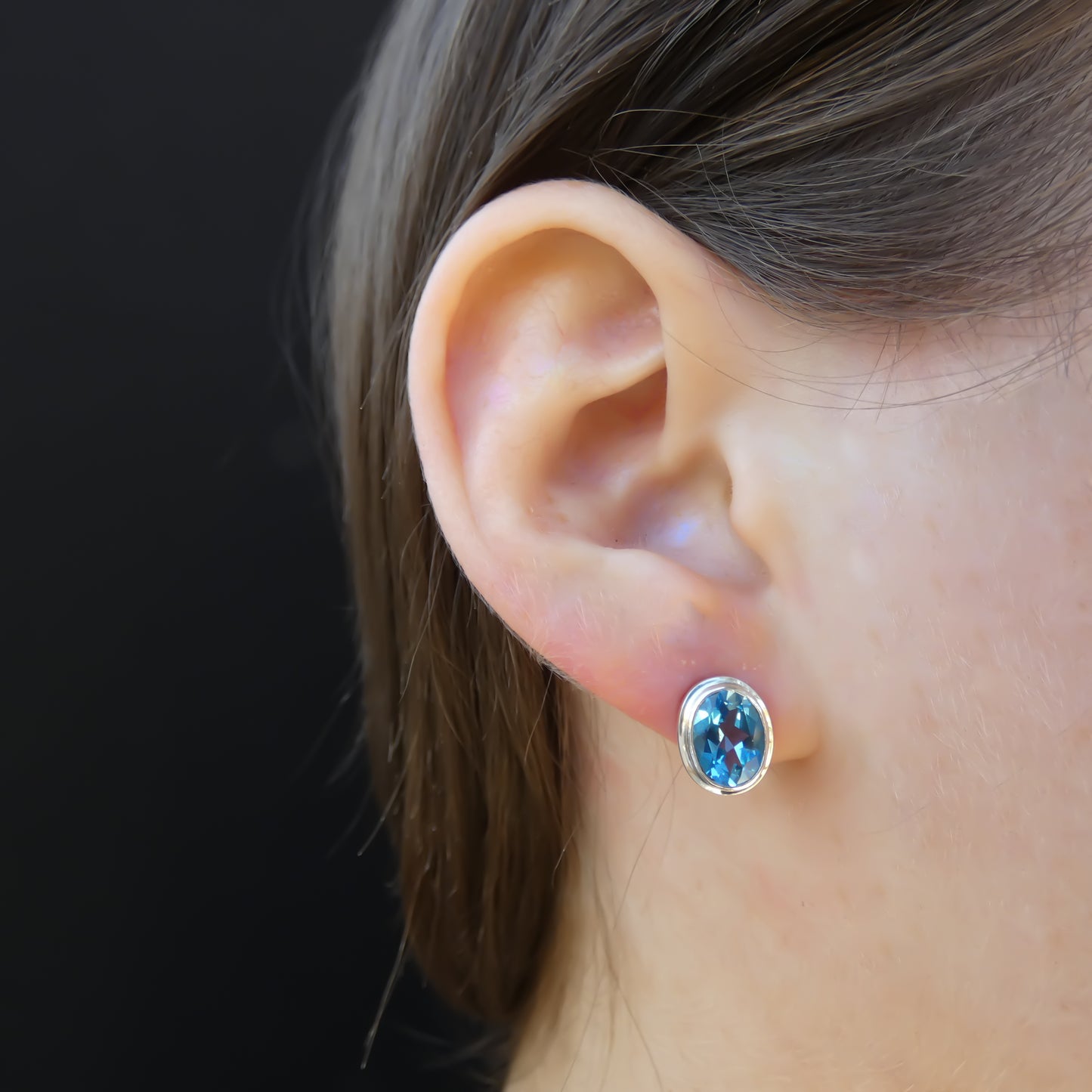 High polish plain setting sterling silver oval post earrings with blue topaz.