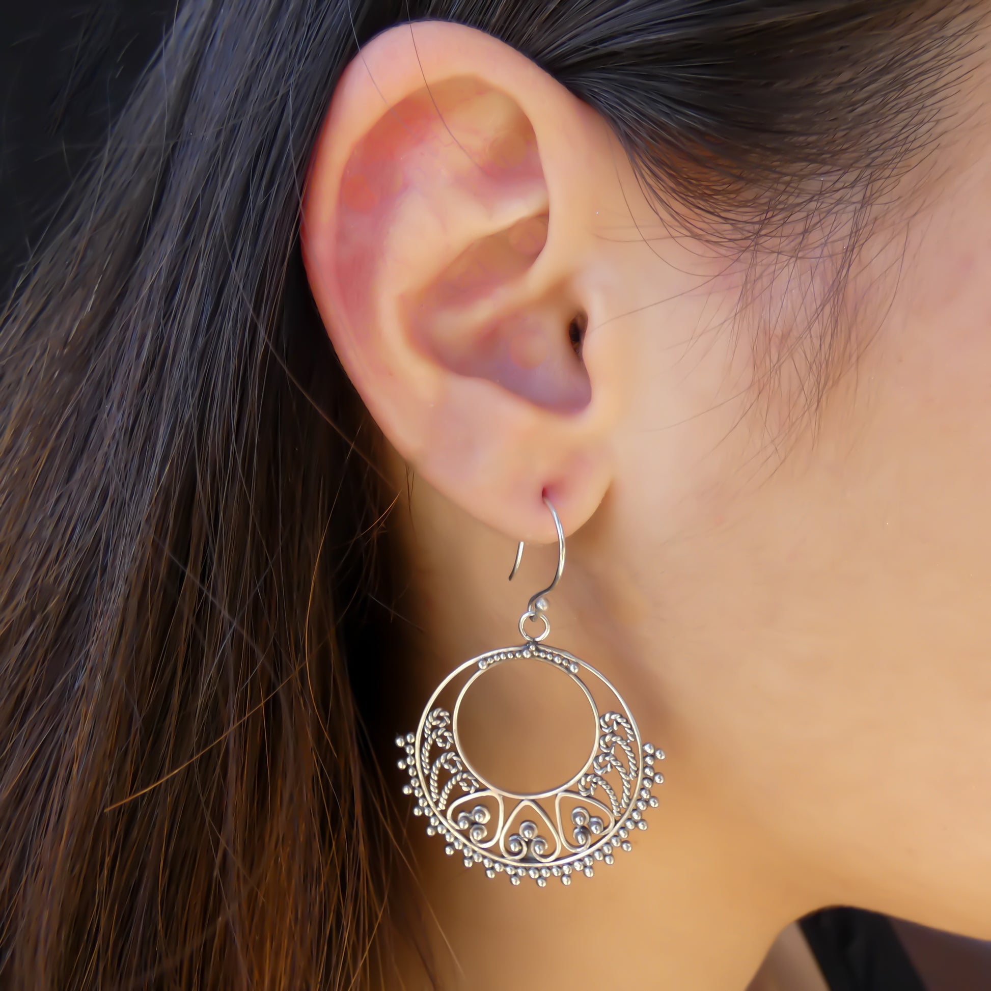 Silver wire and beads drop earrings worn by a woman.