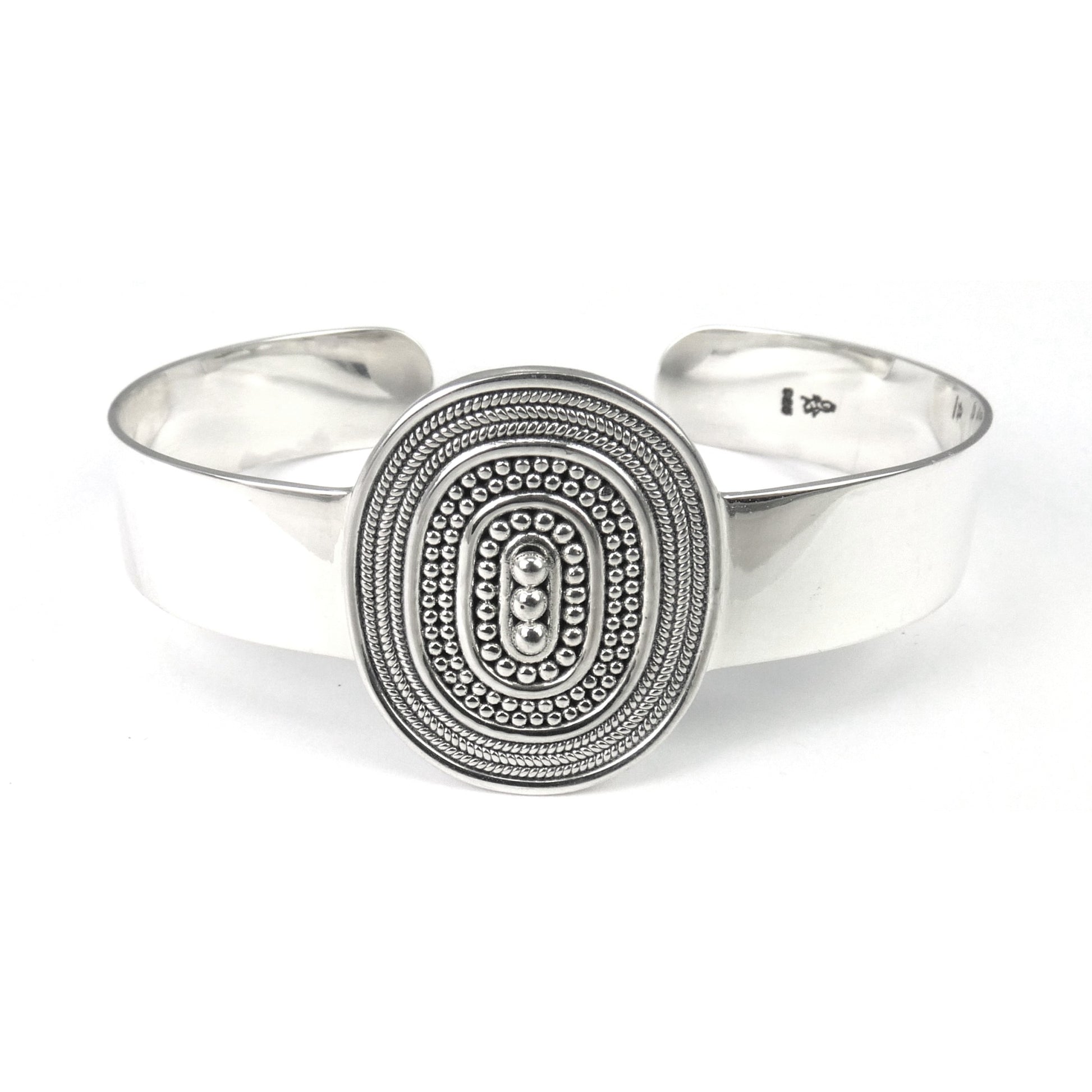 Silver cuff bracelet with one centered oval station with bead and rope decoration.