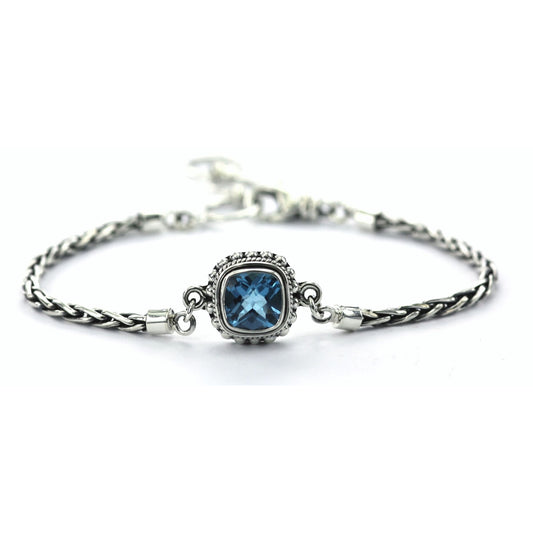 Silver bracelet with single wheat chain arms and one center station with a square blue topaz gemstone.