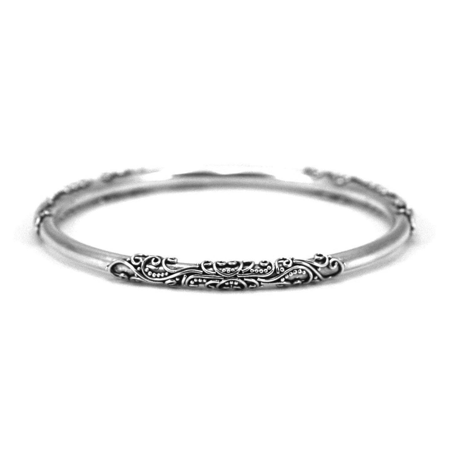 Silver bangle bracelet with three areas of filigree wire adornment.