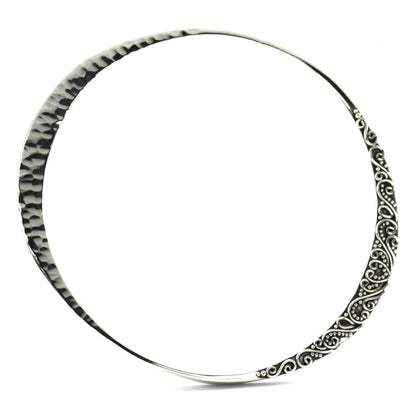 Silver bangle bracelet with a mobius shape and hammered and filigree design elements.