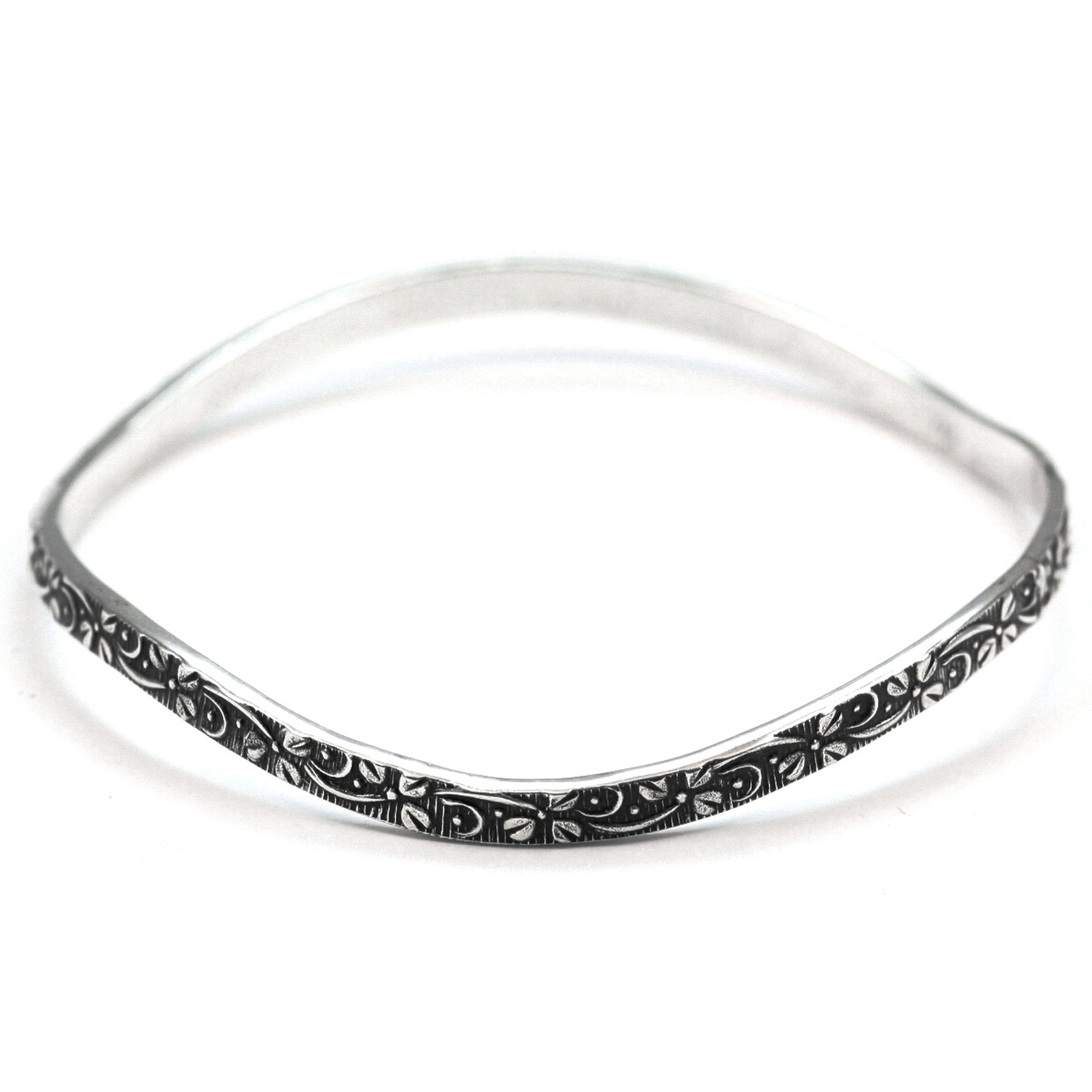 Silver wavy bangle bracelet with floral design motif.