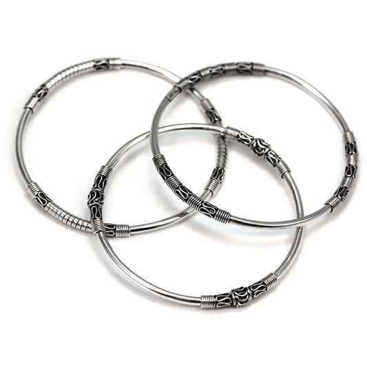 Three silver bangles with traditional Bali filigree design elements.