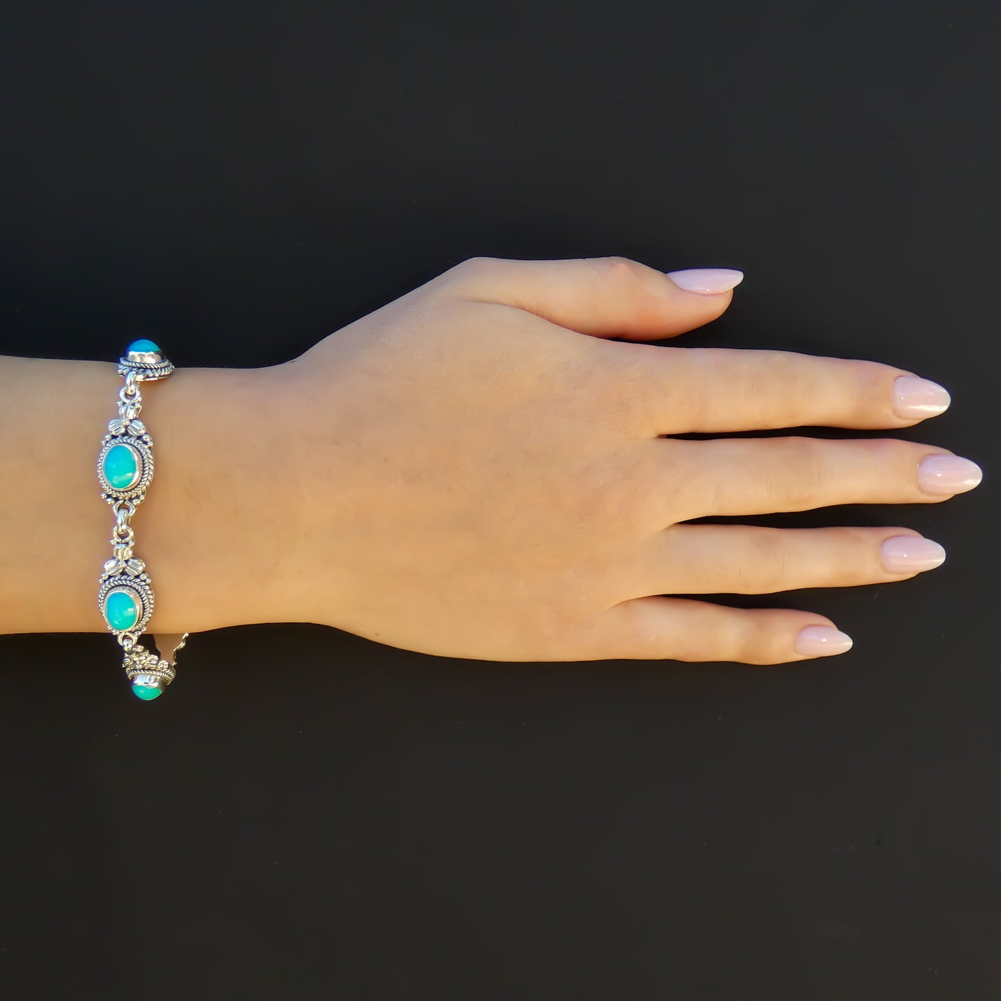 Woman wearing a silver bracelet with amazonite gemstones and floral accents.