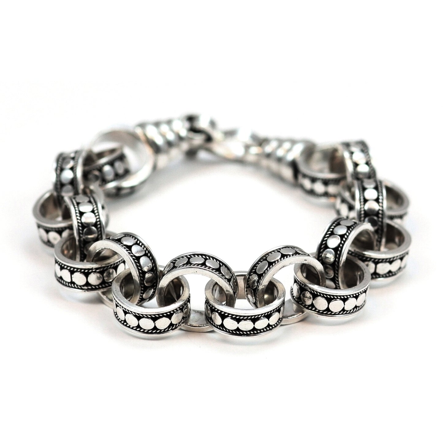 Silver ring link bracelet with polished dots and dark oxidized background.