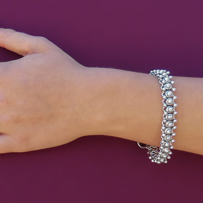 Woman wearing a shiny beaded silver bracelet.