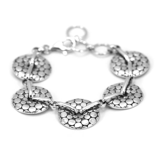 Silver link bracelet made of five round discs with small dots and oxidized background surface.