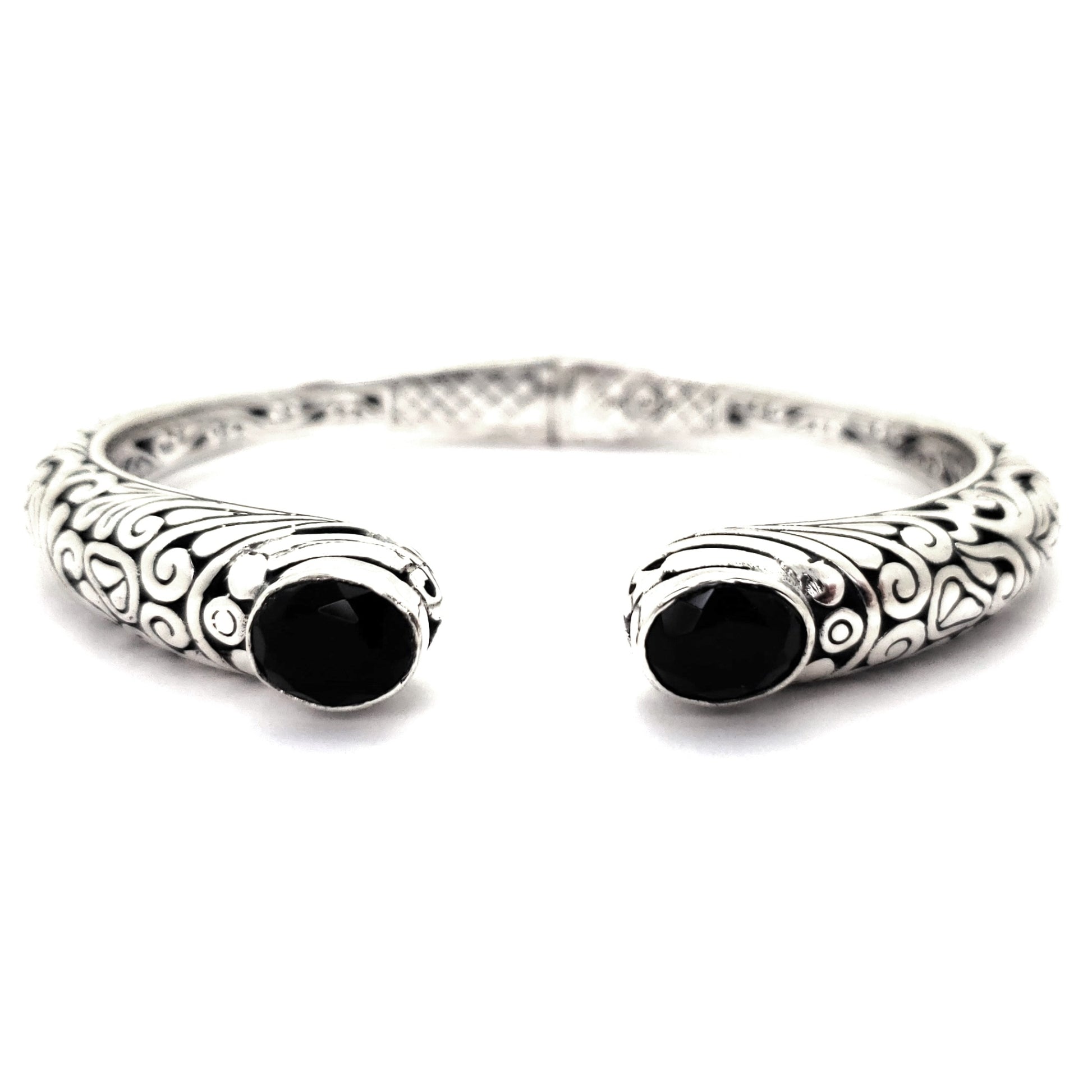 Hinged silver cuff bracelet with carved filigree design and two black onyx gemstones.