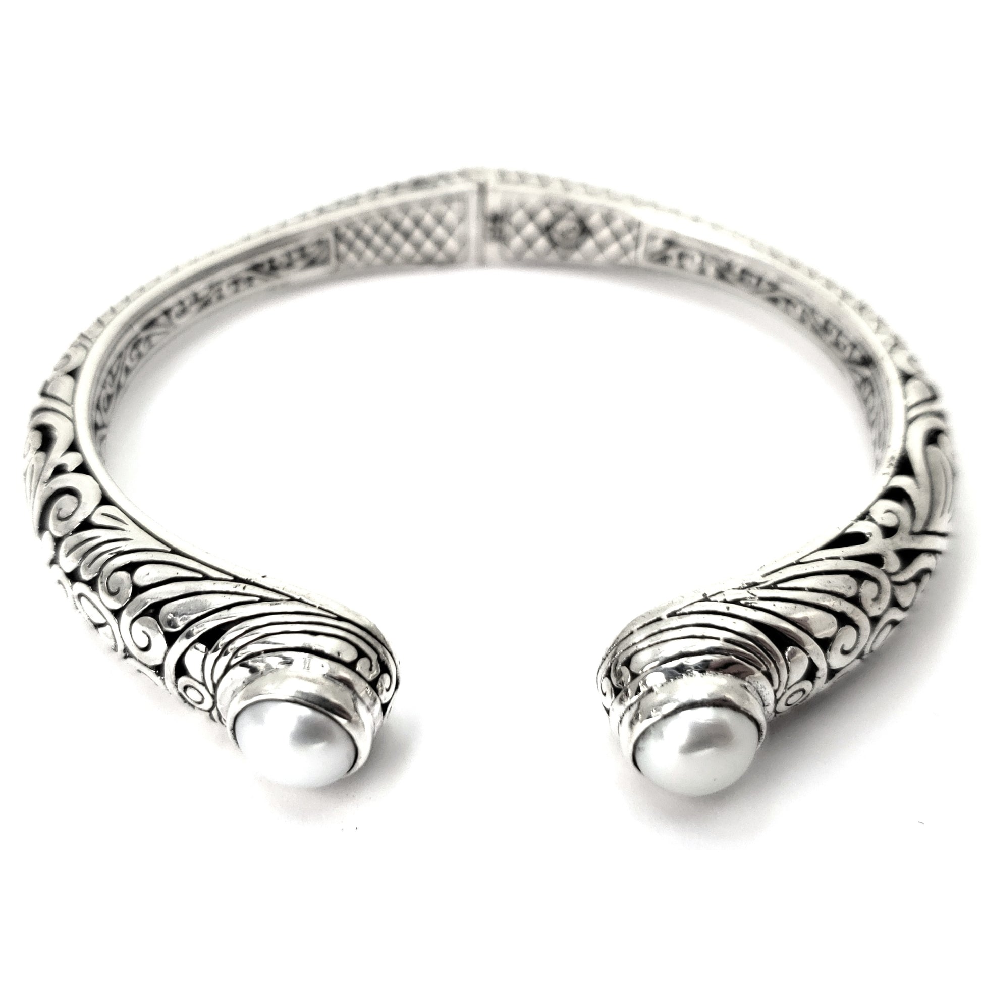 Hinged silver cuff bracelet with carved filigree design and two pearls.