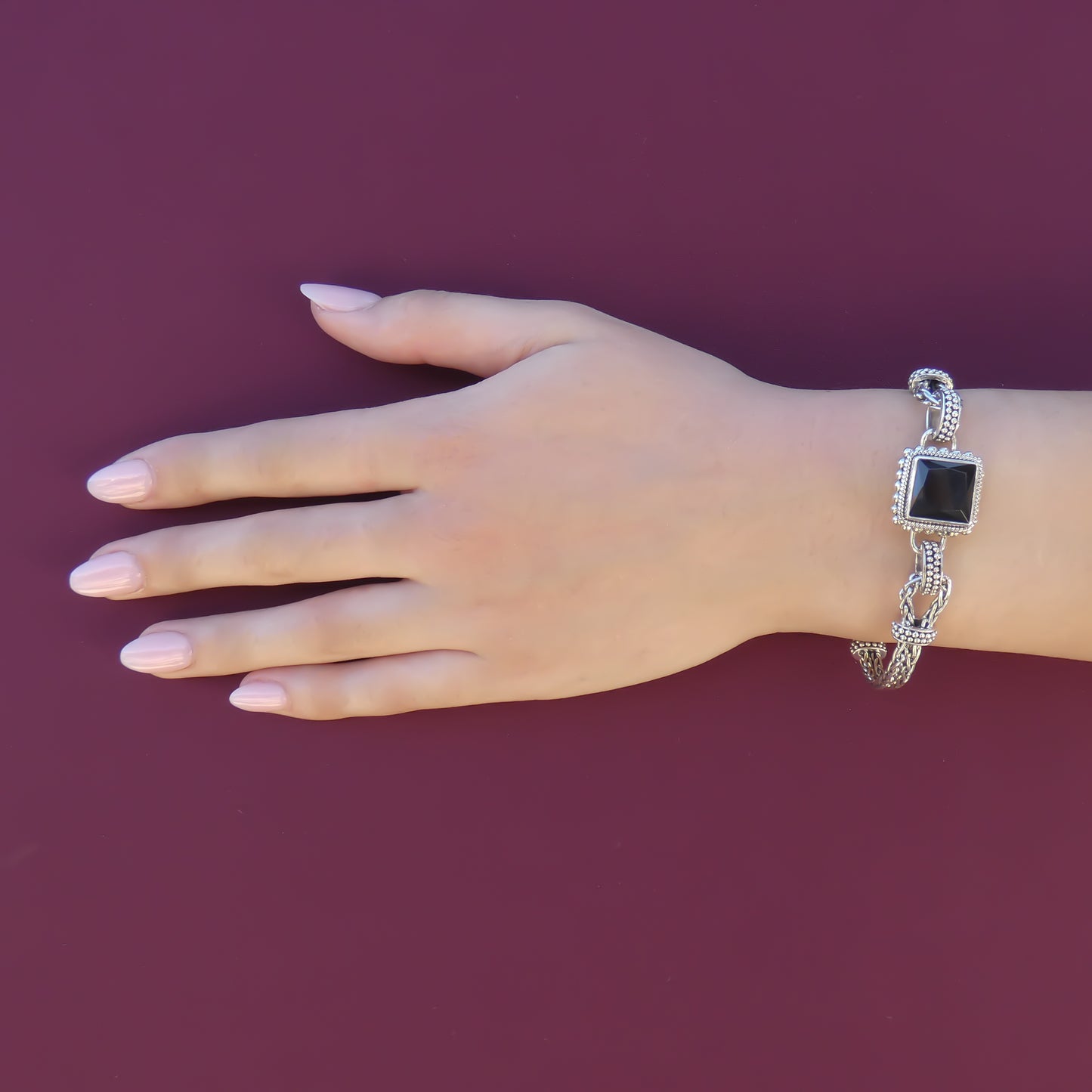 Woman wearing a silver bracelet with a faceted black onyx gemstone.