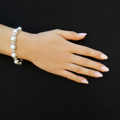 Woman wearing a silver link bracelet with pearls in each link.