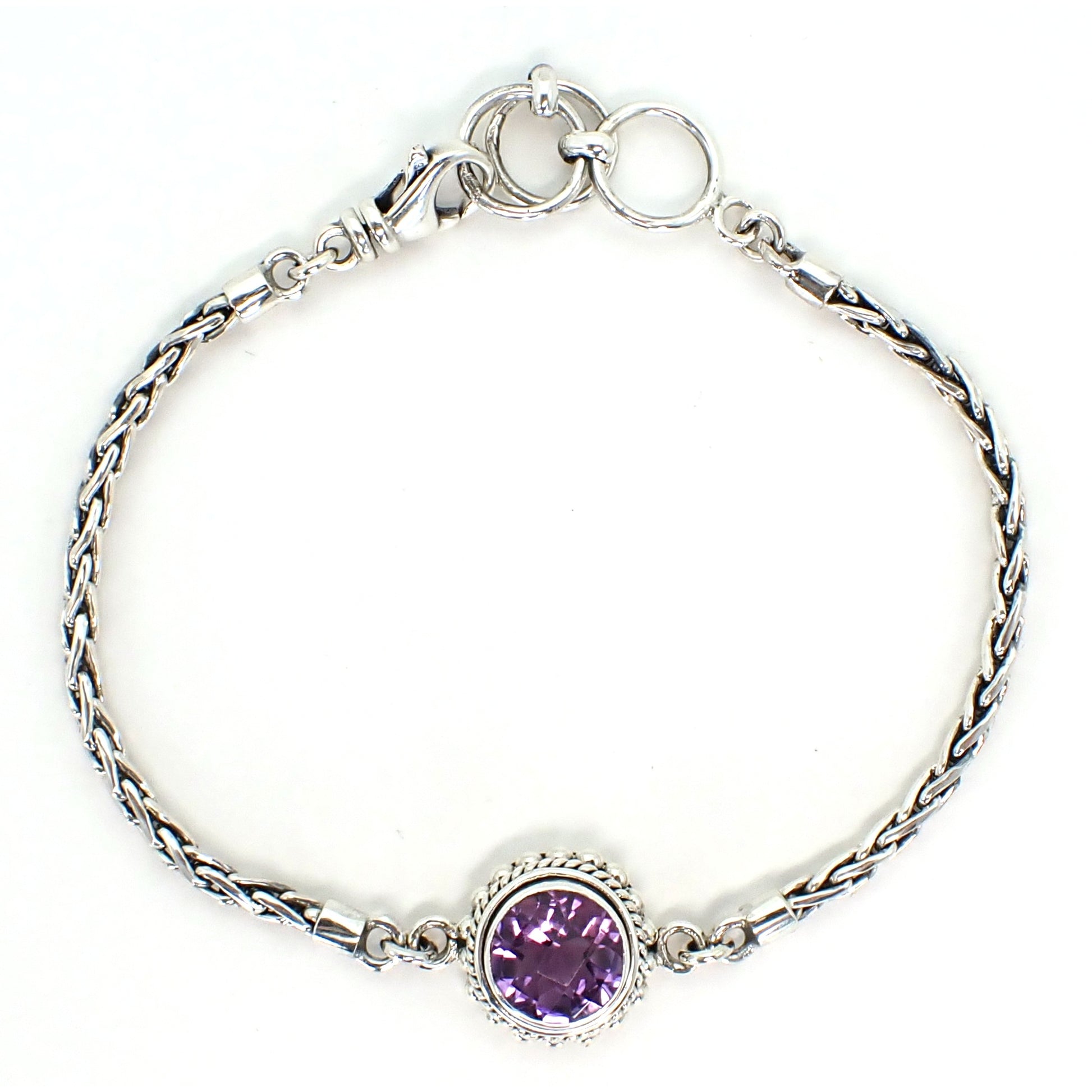 Silver bracelet with wheat chain arms and a single purple, round amethyst gemstone in the center.