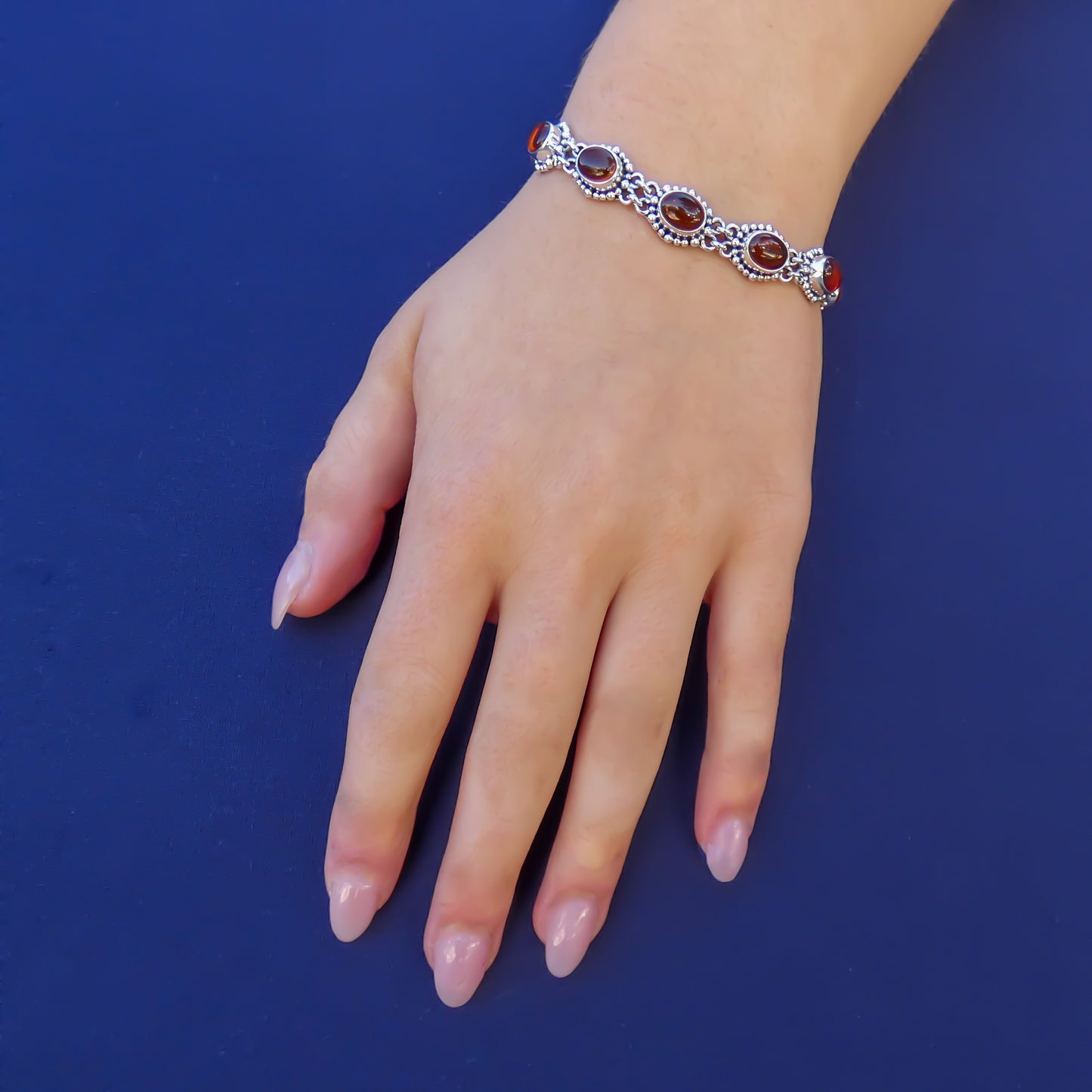 Woman wearing a silver amber link bracelet with beaded accents.