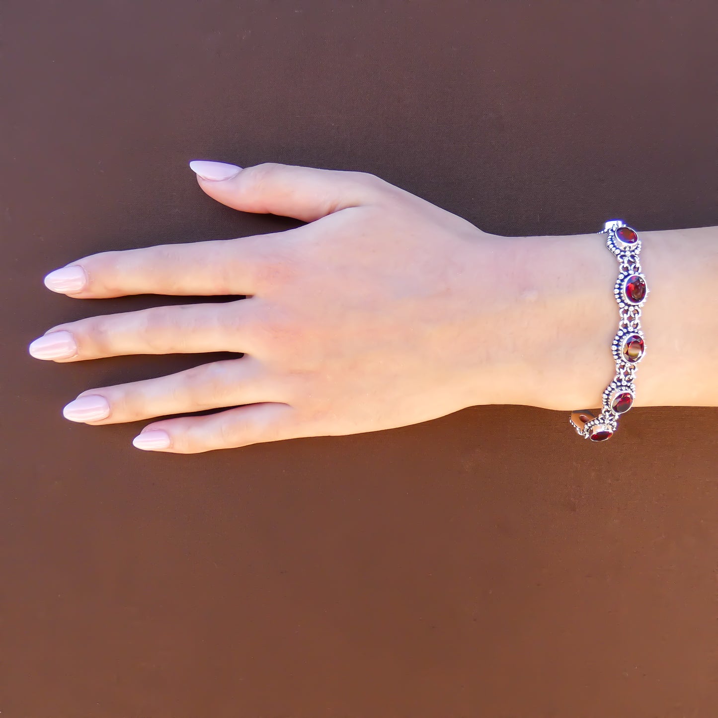 Woman wearing a silver and red garnet gemstone link bracelet.