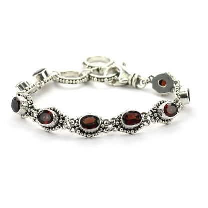 Silver bracelet with nine faceted red garnet gemstones set in beaded links.