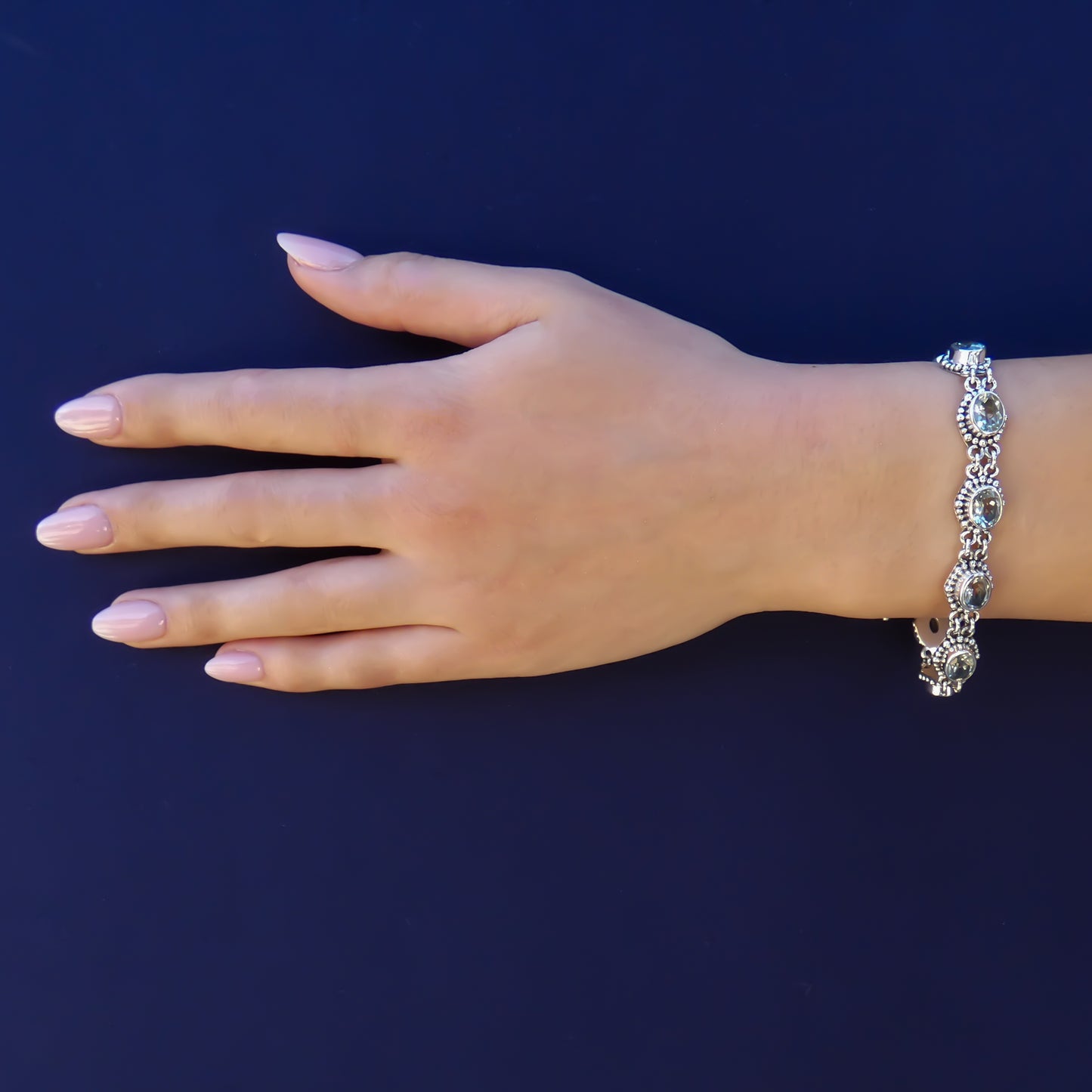 Woman wearing a silver and green amethyst link bracelet.