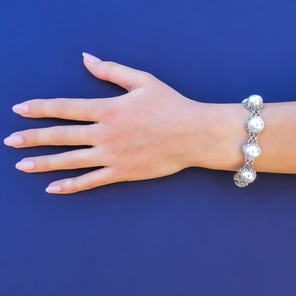 Woman wearing a pearl link bracelet with double ring link connectors.