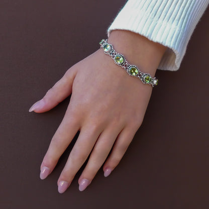 Woman wearing a silver link bracelet with oval green peridot gemstones