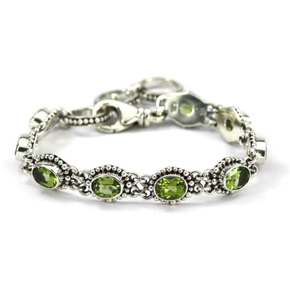 Silver link bracelet with nine green peridot gemstones and beaded borders.