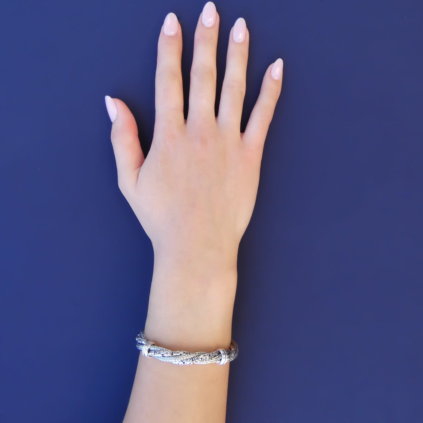 Woman wearing a bracelet made of twisted byzantine and herringbone chains.