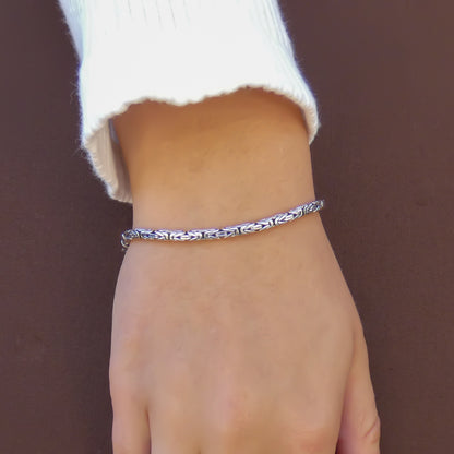 Woman wearing a silver byzantine chain bracelet.