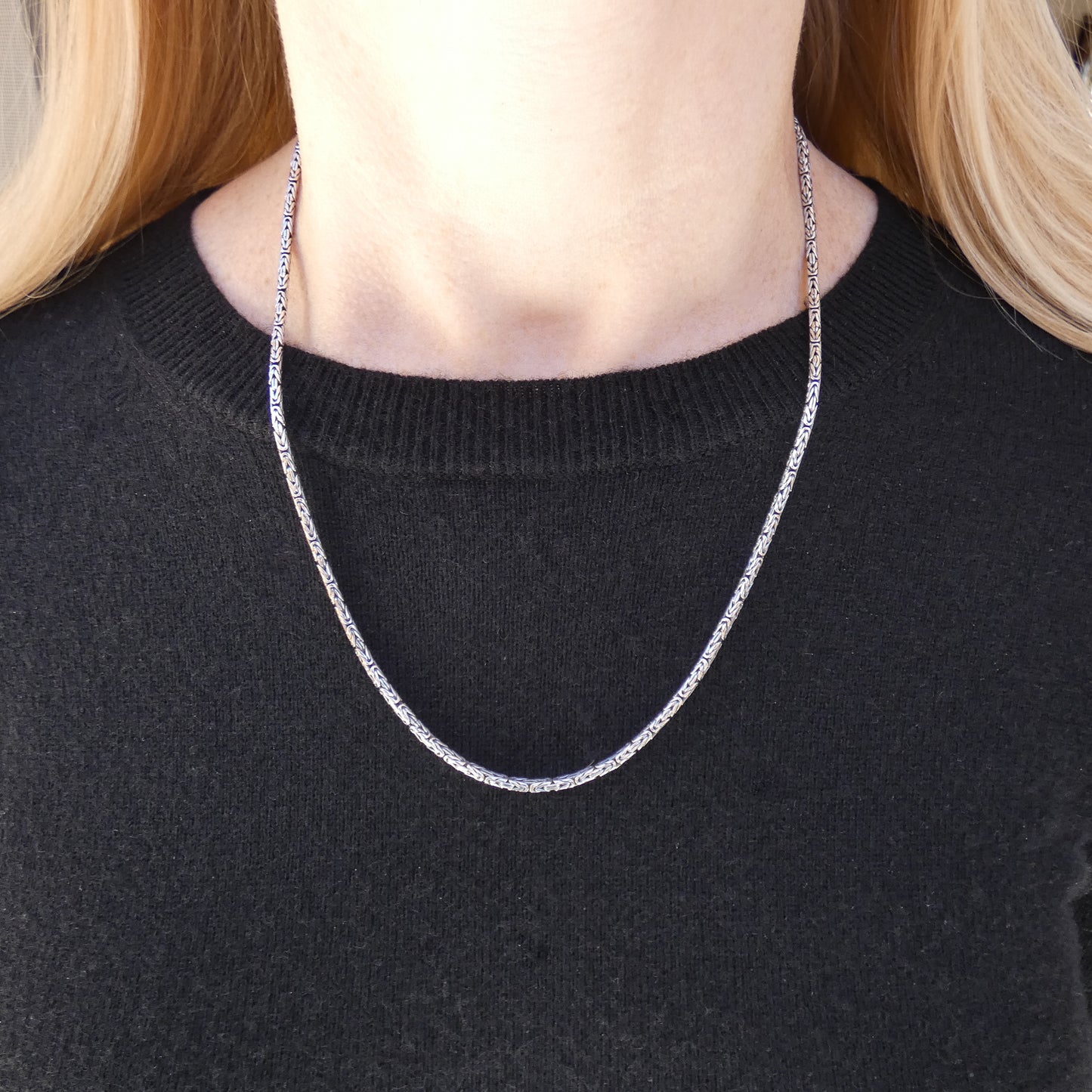 Woman wearing a silver byzantine chain necklace.