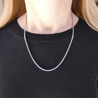 Woman wearing a silver byzantine chain necklace.