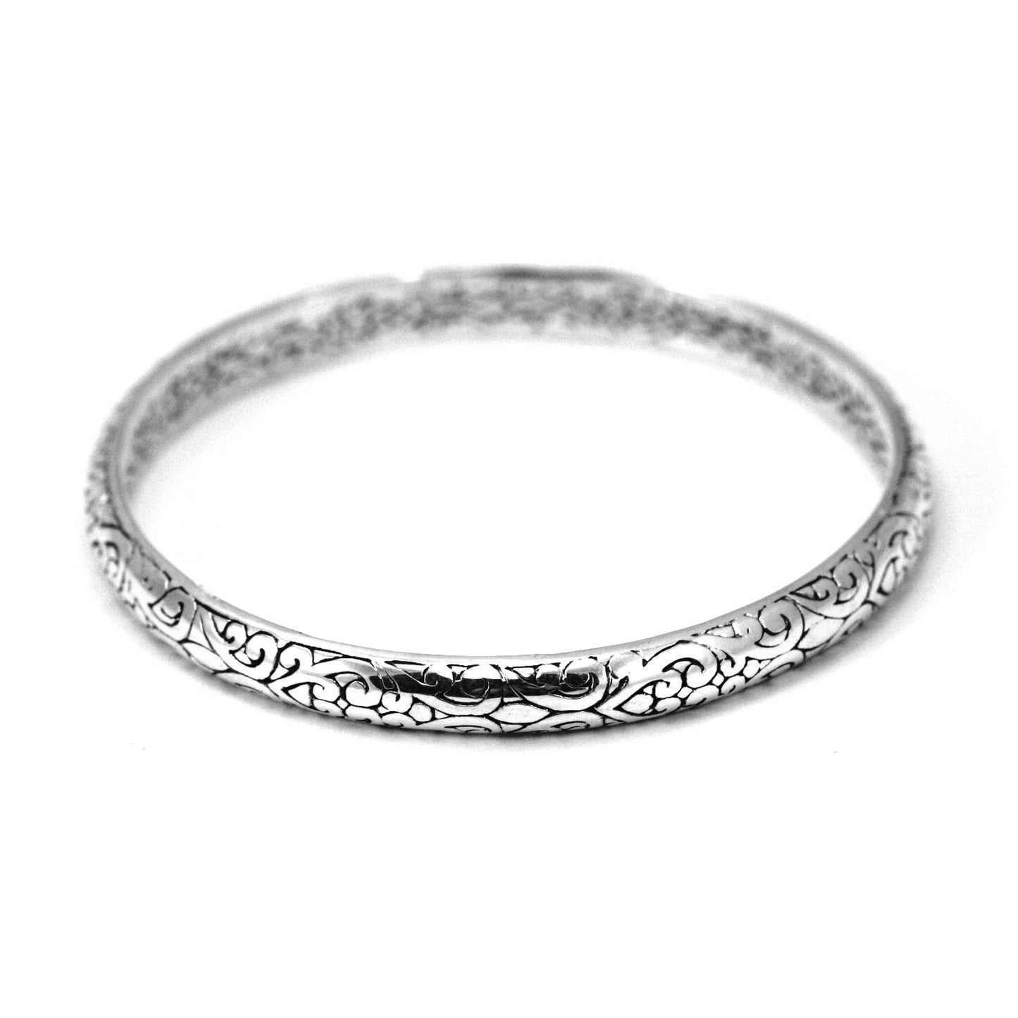Thick and chunky silver bangle bracelet with carved filigree design detail.