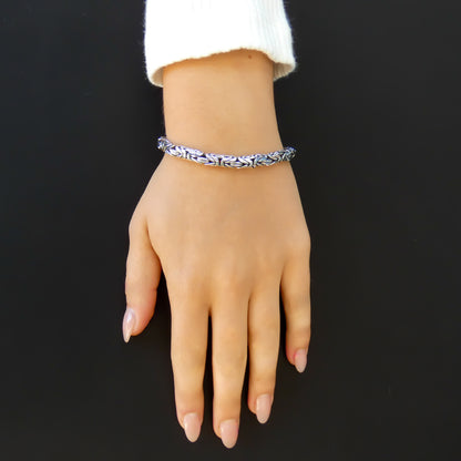 Woman wearing a thick byzantine silver chain bracelet.