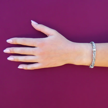 Woman wearing a lightweight silver bracelet made of silver byzantine, wheat and herringbone chains.