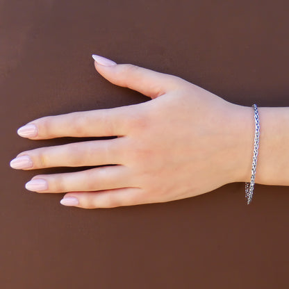 Woman wearing a silver wheat chain bracelet.
