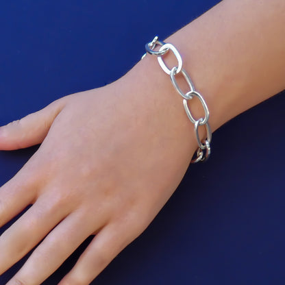 Woman wearing a silver high polish link bracelet.