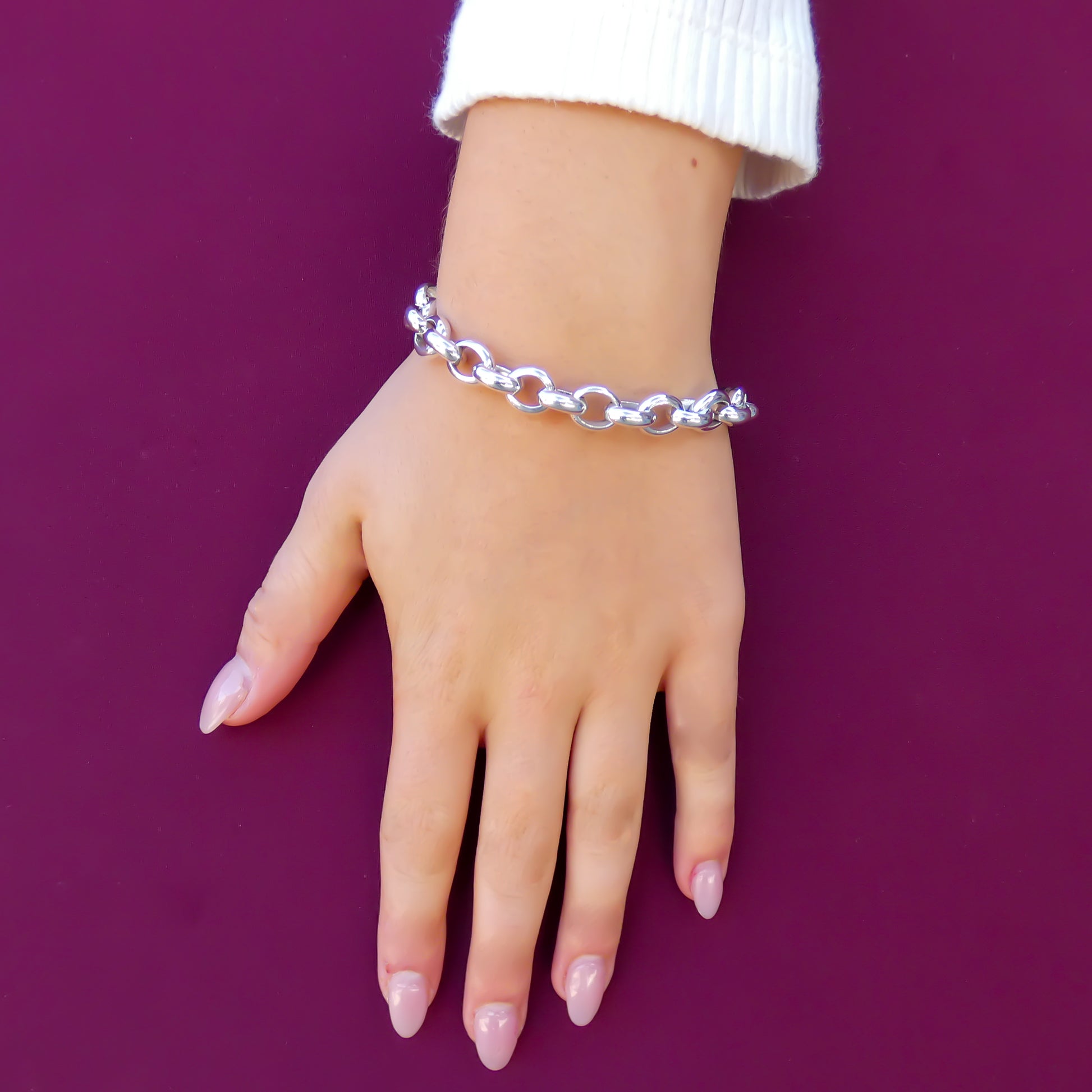 Woman wearing a silver rolo-style link chain bracelet.