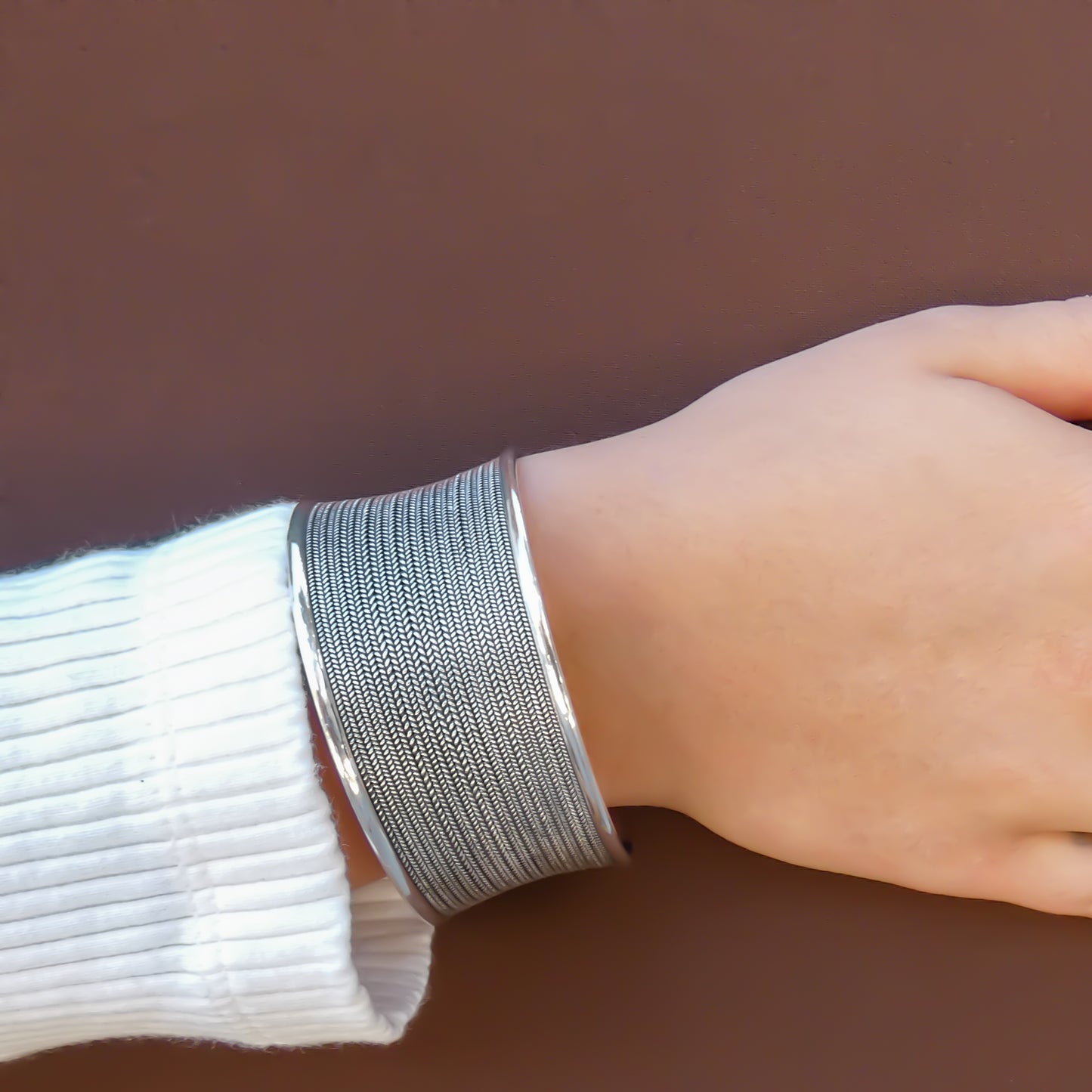 Woman wearing a bold, wide silver cuff bracelet.