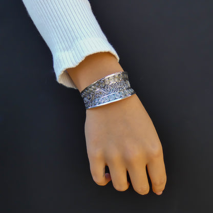 Woman wearing a curvy ornate silver cuff bracelet.