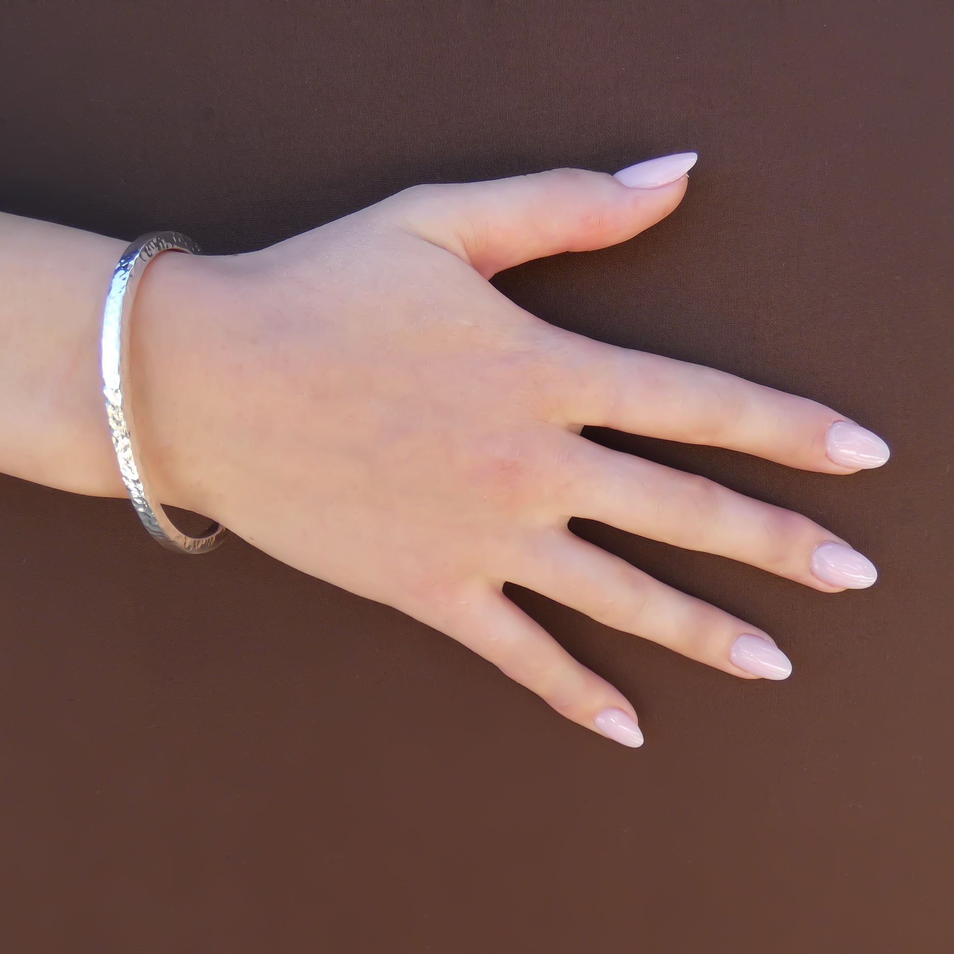 Woman wearing a hammered cuff bracelet with a square profile.