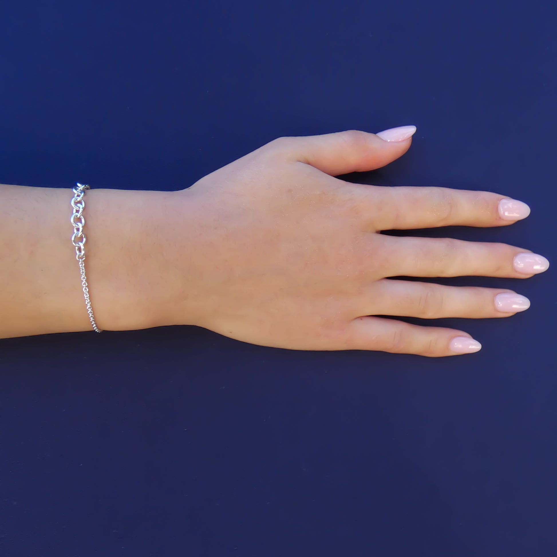 Woman wearing a silver bracelet with two different chain styles end to end.