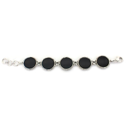 Bracelet laid out flat made of five round links with black onyx discs and silver borders.