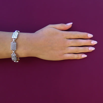 Woman wearing a silver link bracelet with three different designs on rectangle links.