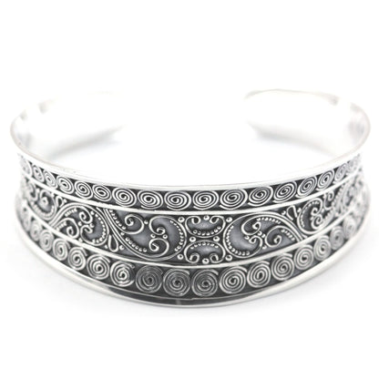 Silver cuff bracelet with ornate wire filigree and bead work on the surface.