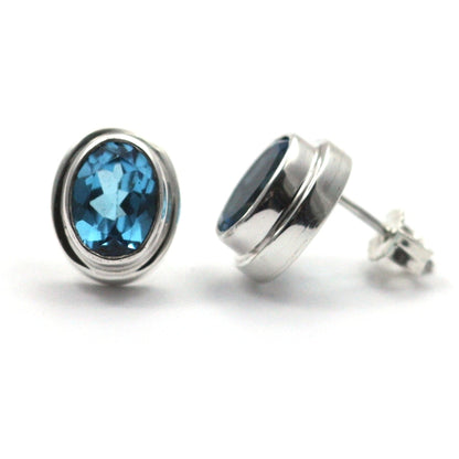 High polish plain setting sterling silver oval post earrings with blue topaz.